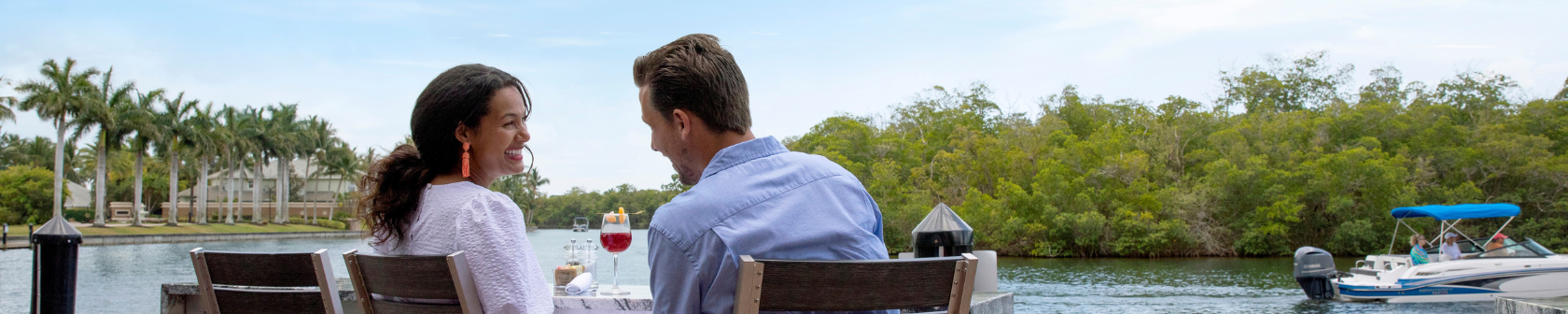 A man and a woman enjoy lunch on a canal in Cape Coral as a boat drives by