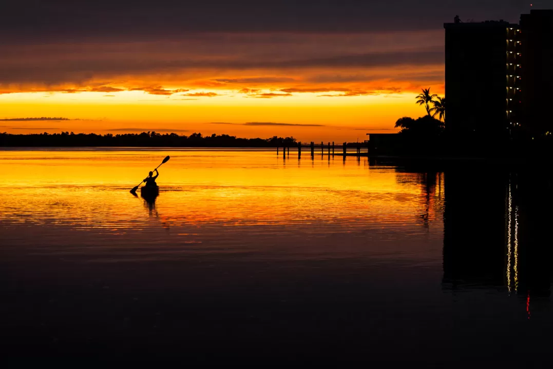 Silhouette of a lone kayaker returning to the shore at a vibrant sunset