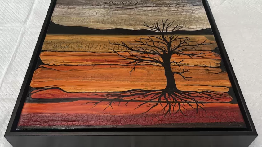 landscape painting of a barren tree against red, orange, yellow and white background with hills in the back.