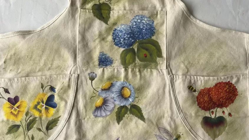 beige apron with different flowers painted on it.