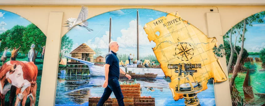 A man walks along a colorful map mural in downtown Bonita Springs