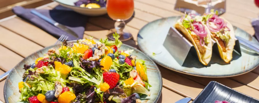 A table topped with plates of food next to a body of water