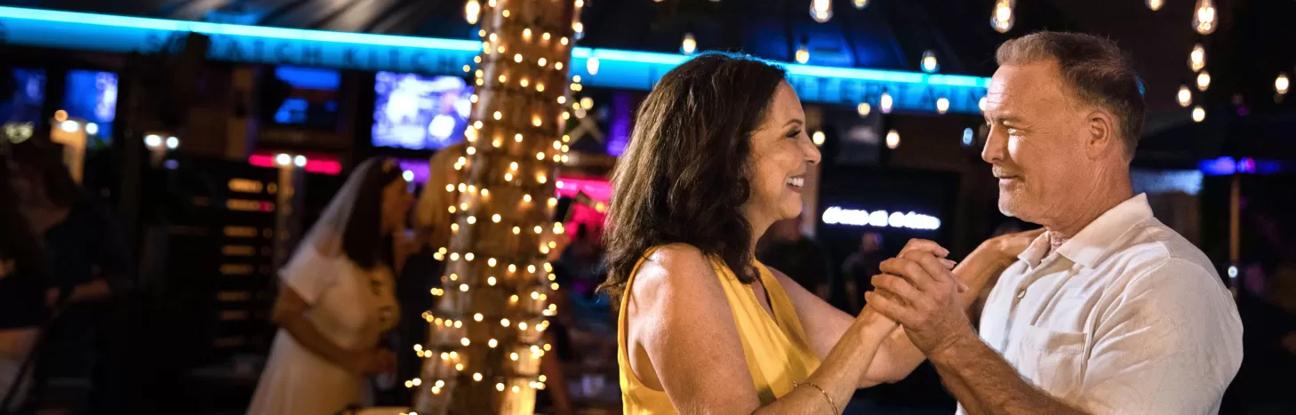 A man and a woman dance at an outdoor bar